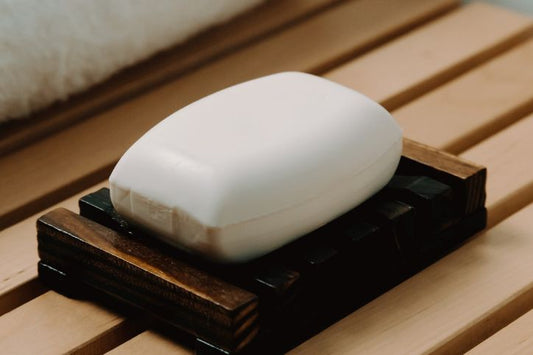 Amber bamboo shower curb on which rests a soap dish with its white soap and a white towel folded in 4.