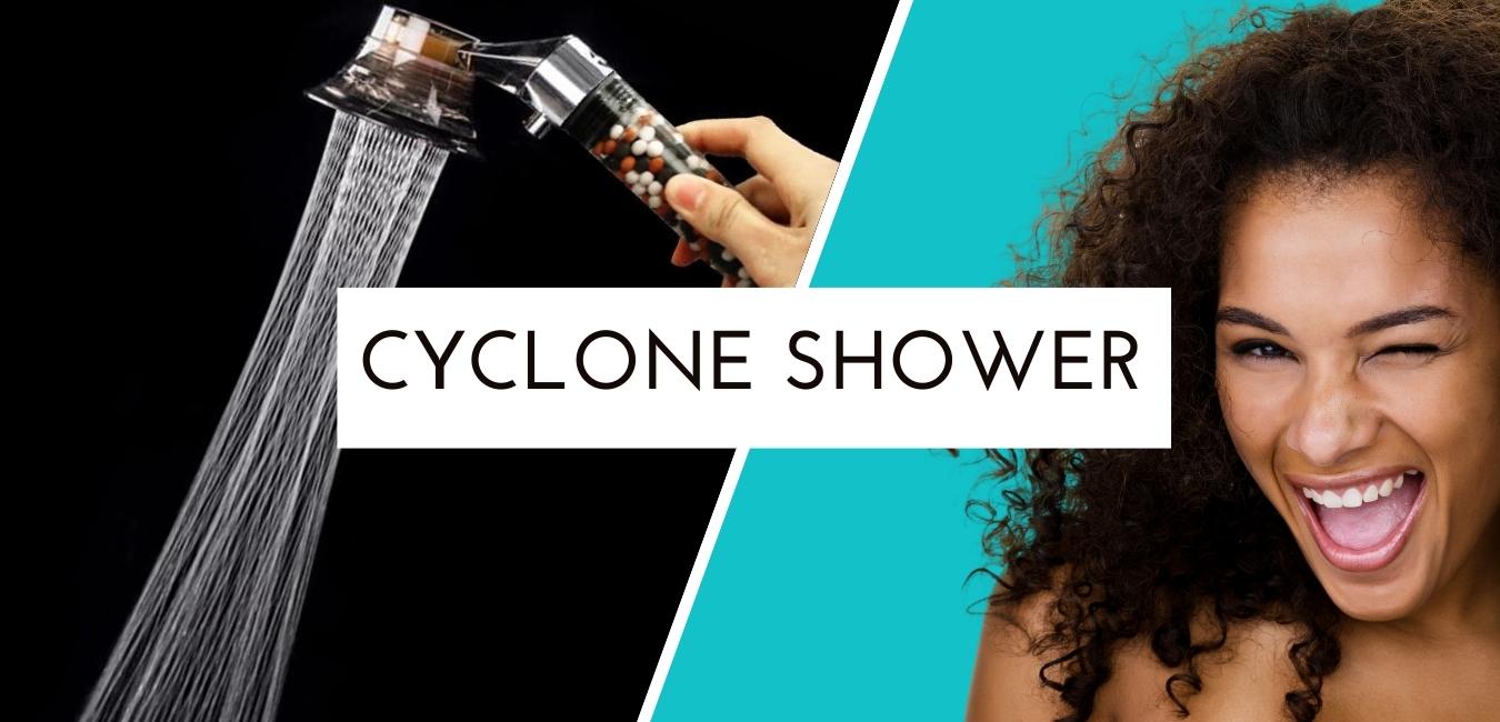 Best Shower Head from Cyclone Shower™ in the center. The picture shows a radiant woman winking with a nice smile. We also see on the left of the woman the shower head with a vintage and elaborate design with filtering beads and its cyclone-shaped jet. 